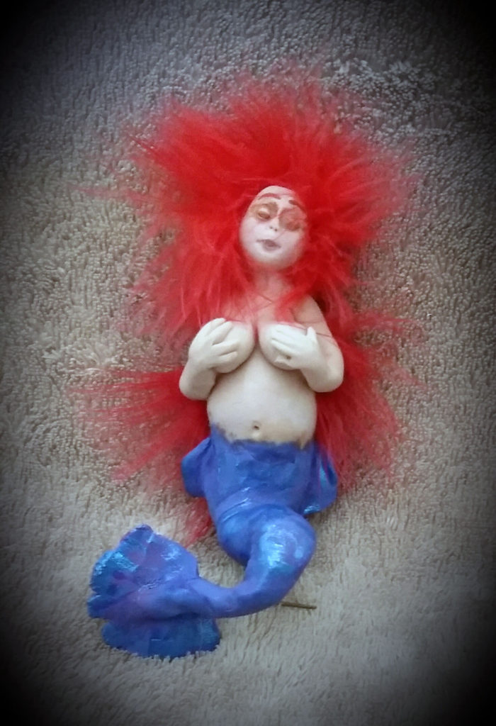 Little blue tailed mermaid with red hair made out of clay by Tina Parsons